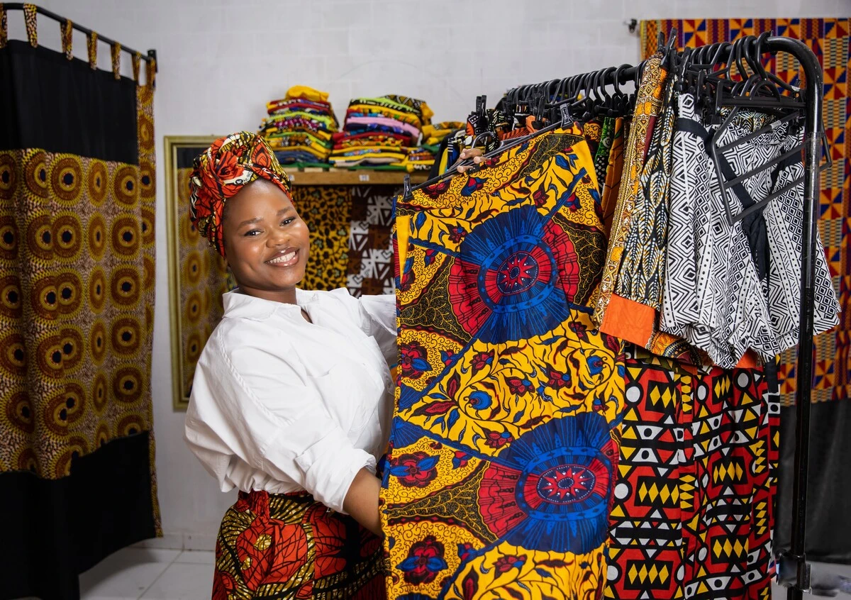 Uma mulher segurando uma saia na sua loja, representando a moda sustentável, tema na COP 30.