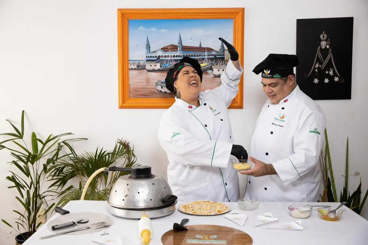 Um casal sorrindo por saber como empreender com pouco dinheiro enquanto preparam encomendas feitas ao negócio deles.