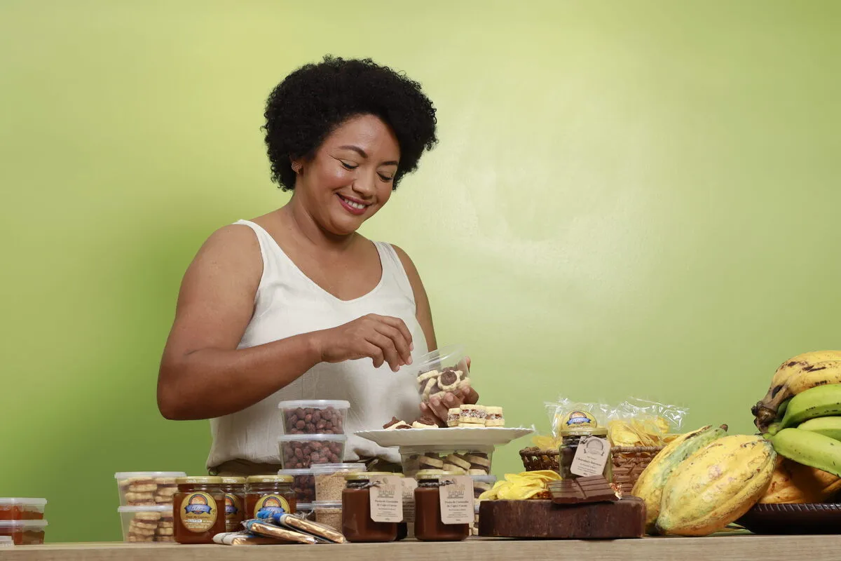 Uma empreendedora organizando os itens em um mostruário, sorrindo por usar tecnologias verdes antes de serem discutidas na COP 30.